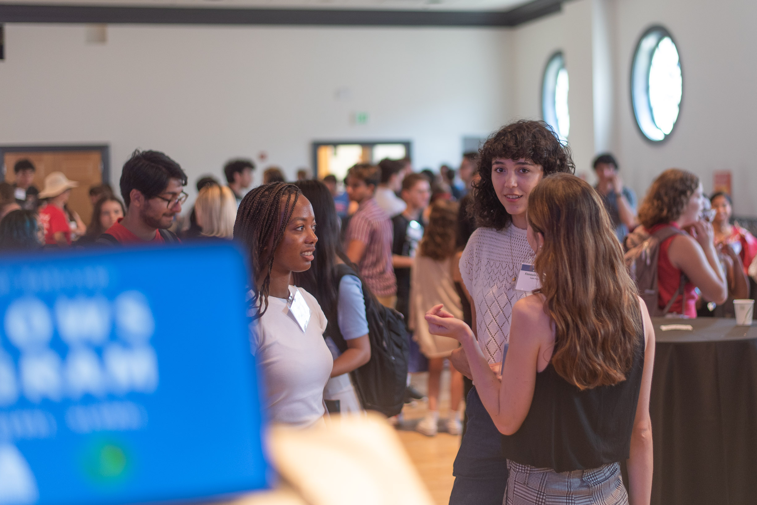 groups of students chat in a ballroom