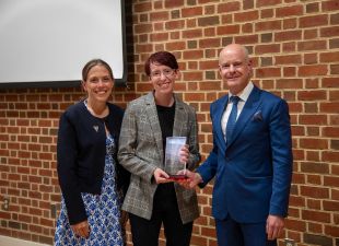 Kristy Maddux, student and Dean Cohen pose with award plaque